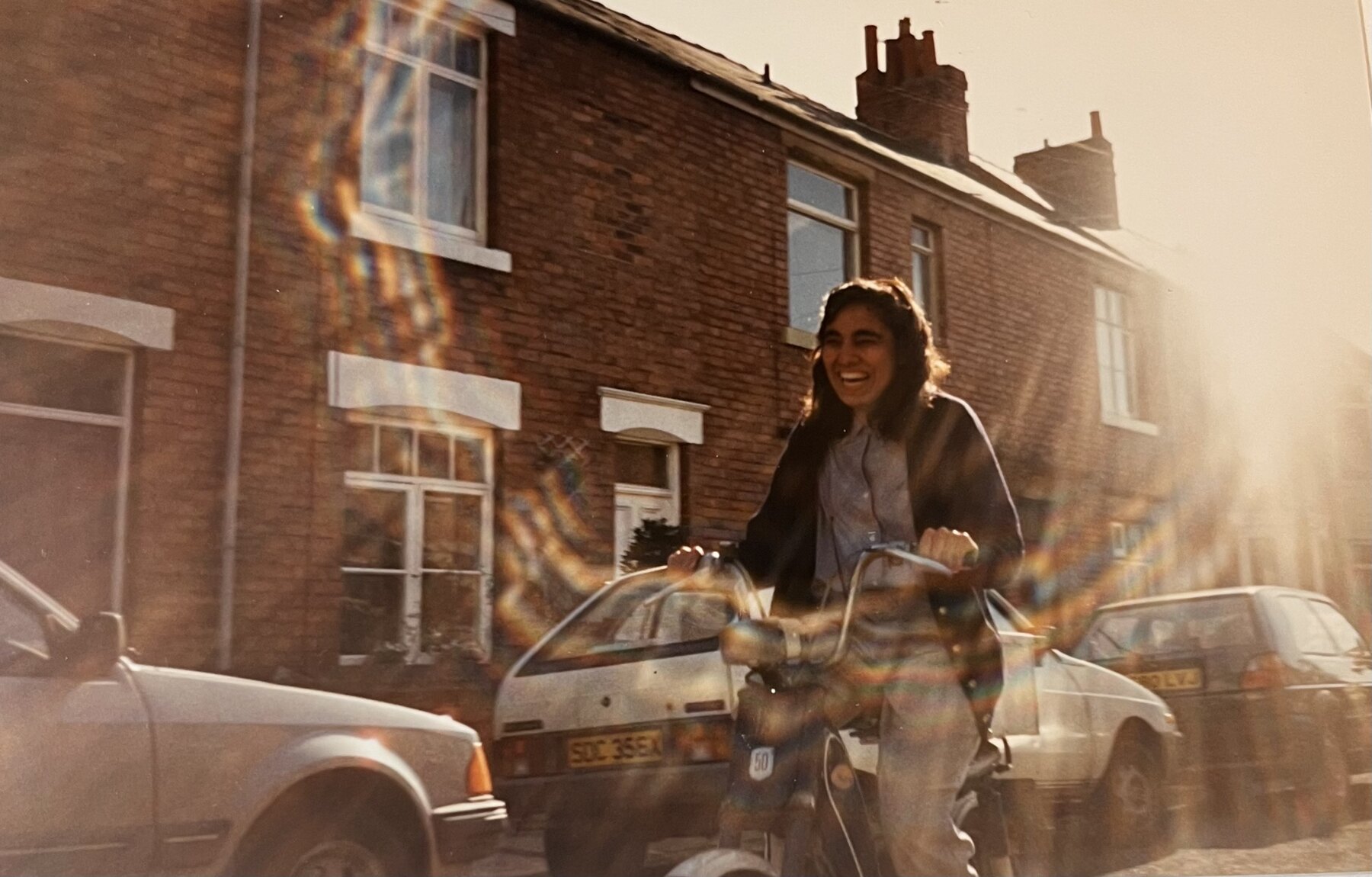 A laughing cyclist passing through intense late sunlight and lens flare